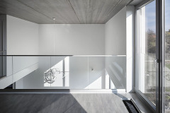 Kombinace bílé hladké omítky se světlou plechovou střechou a hliníkovými okny se propisuje i do interiéru, do světlých neutrálních odstínů podlahy a nábytku