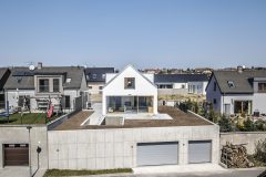 Garáž vyrovnávajíci vyškový rozdíl mezi přiléhajícími ulicemi tvoří podstavu domu