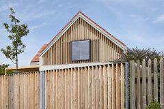 Ve štítech nové sedlové střechy jsou velká okna, která stíní a částečně zakrývají modřínové lamely