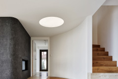 Oboustranný krb je zabudovaný do černé terrazzové stěny, z chodby se čistí a přikládá dřevo