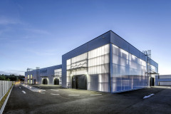 Obvodový plášť tří hal byl realizován z PUR panelů a panelů z mléčného polykarbonátu. Polykarbonátová fasáda částečně odhaluje dění uvnitř.