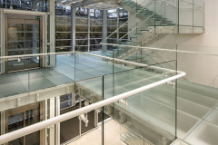 Skleněné schodiště a skleněné podlahy propouštějí sluneční paprsky celou halou a dodávají tak interiéru lehkost