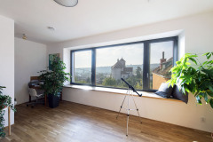 Společenská část zabírá celé prostřední podlaží a pokračuje na terasu. Výhled na město rámuje panoramatické sedací okno