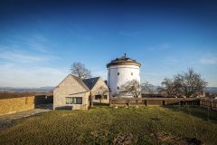 Novostavba obytného domu svou velikostí neohrožuje dominantu bílé válcové hmoty větrného mlýna. Nenarušuje ani pohledové osy, které k němu směřují.