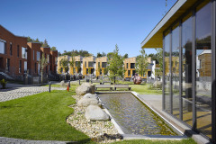 Mezi domy vzniklo náměstí s komponovanou zelení, sochařskou výbavou, vodní plochou a lavičkami. Součástí parku je také prosklená klubovna.