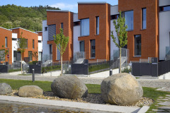 Zešikmené střechy mají úžlabí kolmo k uliční frontě. Bělostnou omítku ustupujících částí doplňuje keramický obklad.