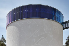 Kruhová loď kostela má ve výsledku fasádu z břízolitu, ozdobenou symbolickými motivy